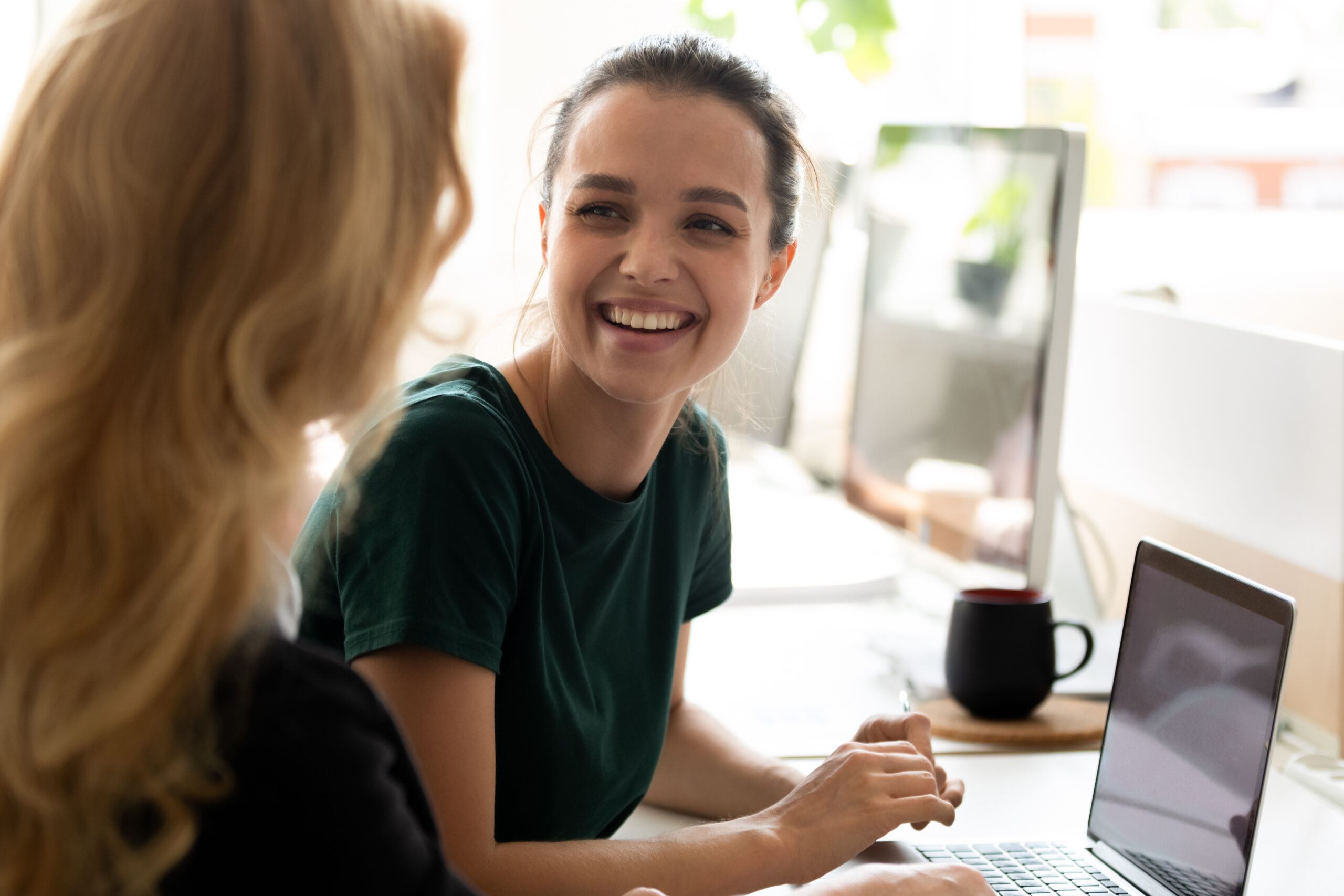 senior business woman working on laptop with assistant writing notes.